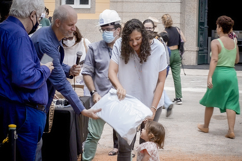 O diretor do MN/UFRJ entrega para a pequena Yeva, afilhada de Gabriela Evangelista, o envelope com as produções das crianças da vida dos funcionários da instituição